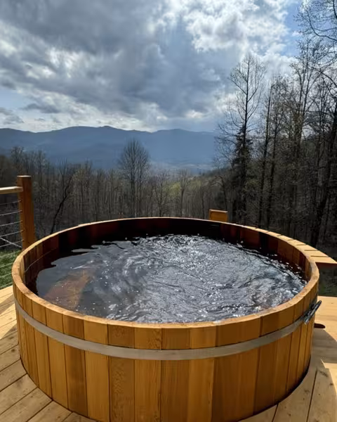 The cedar hot tub on the deck with the mountains behind it