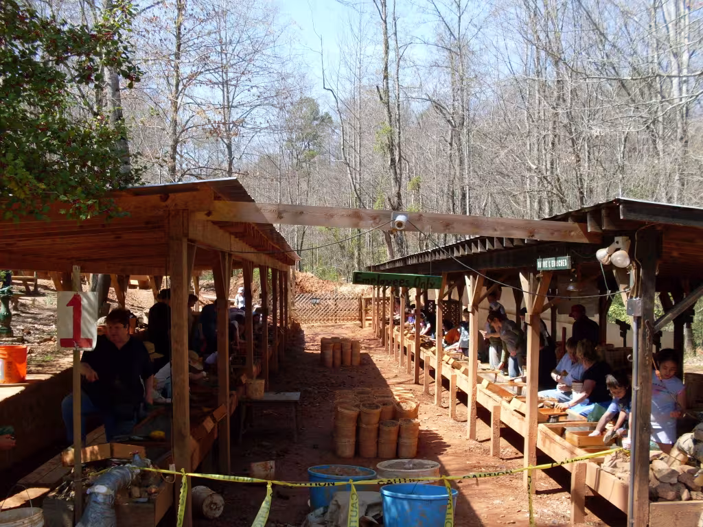 A covered wooden gem-mining flume with rows of buckets and screens
