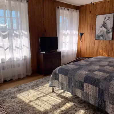 Queen bedroom with plaid quilt in the Kress Family Suite