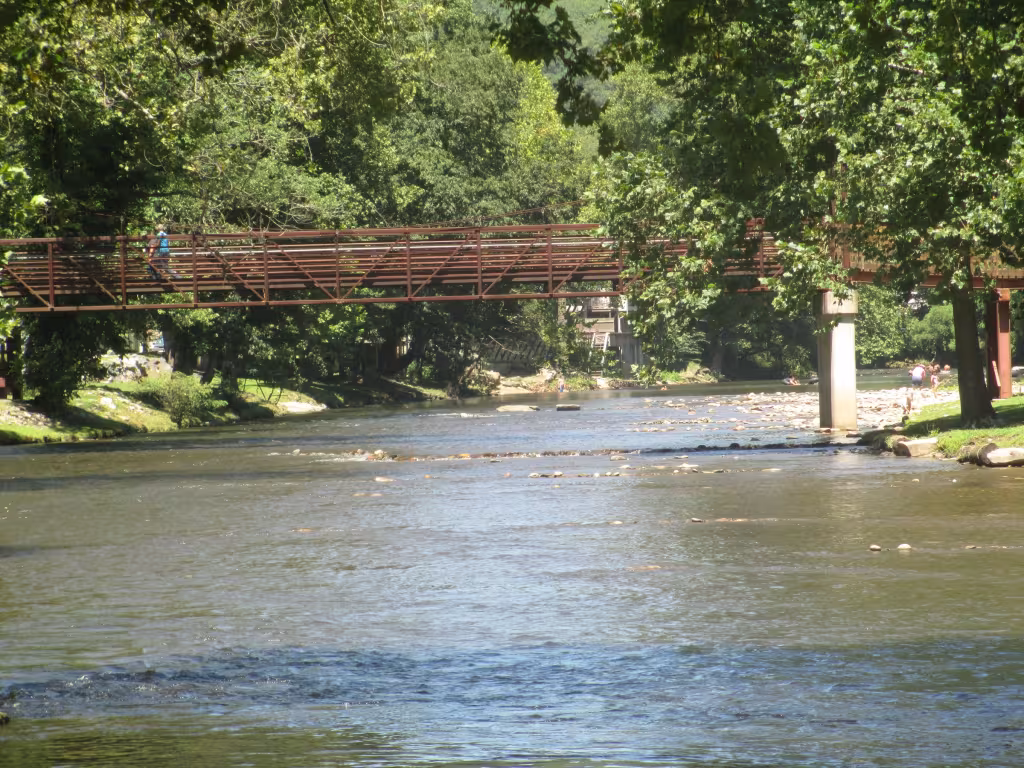 The Oconaluftee River running wide and shallow under a footbridge in Cherokee
