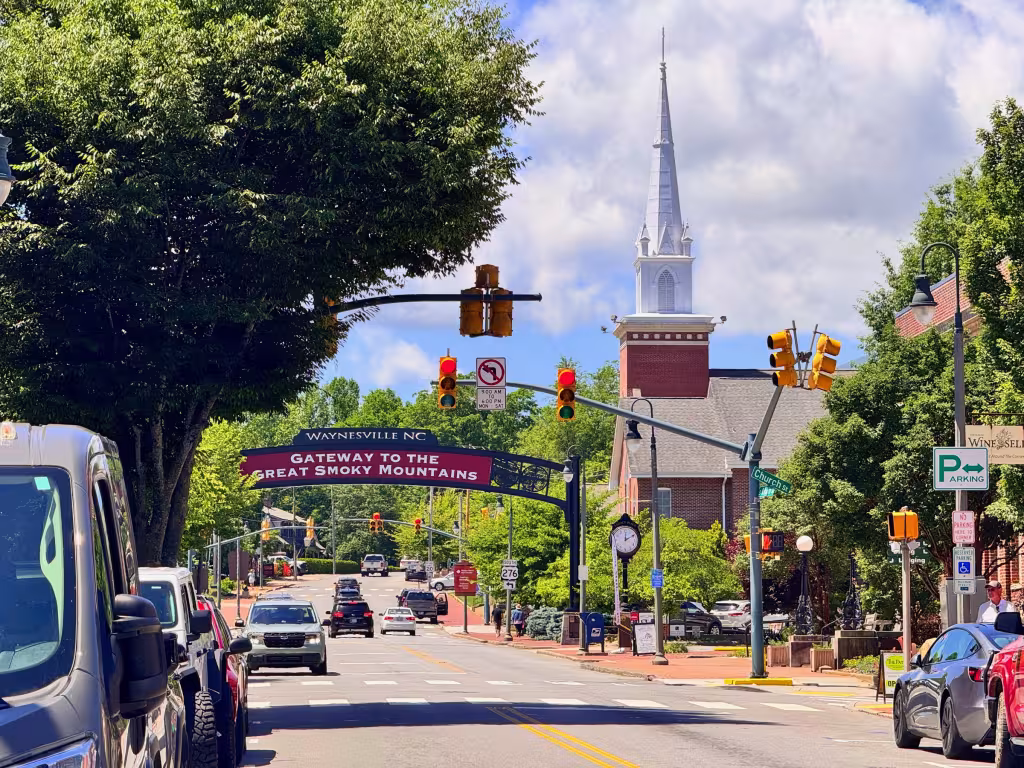 Main Street in Waynesville under the Gateway to the Great Smoky Mountains banner, with a white church steeple behind